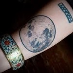 Фото тату с изображением луны и римских цифр. Оригинальный рисунок татуировки в черно-зеленой гамме.