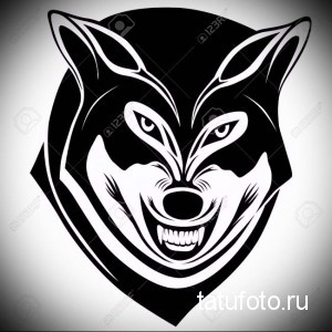 Фото стилизованной татуировки головы волка в черном цвете на белом фоне, с геометрическими элементами.