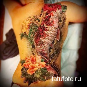 Фото татуировки карпа кои на спине, окруженного цветущими пионами. Татуировка выполнена в ярких цветах.