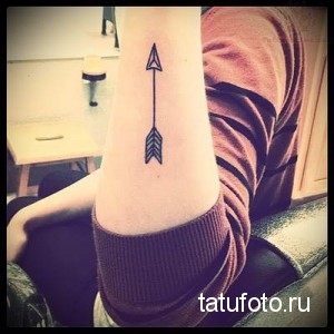Фото тату: простая черная стрела на запястье, выполненная в минималистичном стиле с акцентом на четкие линии.