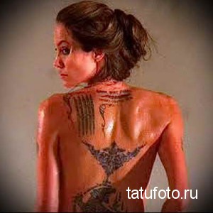 Фото тату на спине Анджелины Джоли с кхмерскими письменами, выполненными черными чернилами. Детализированный рисунок татуировки на женской спине.