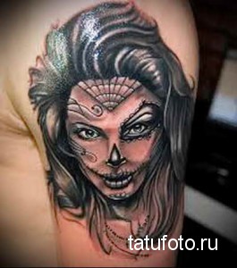 Фото тату: портрет девушки с элементами сахарной черепушки (Santa Muerte) на плече, выполненный в черно-белой гамме с яркими акцентами.