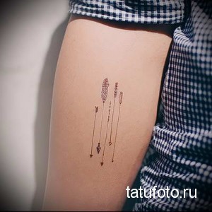 Фото тату на бедре с изображением нескольких минималистичных стрел, выполненных тонкими линиями. Небольшой рисунок татуировки черным цветом.