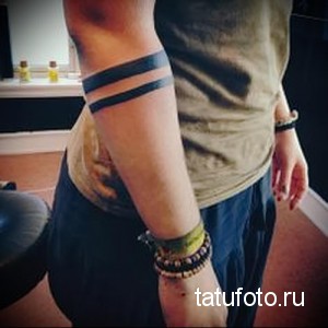 Фото тату на предплечье с изображением двух параллельных черных линий, образующих браслеты. Минималистичный дизайн, лаконичность.
