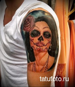 Фото тату на плече: девушка в стиле Sugar Skull с розой в волосах, выполненная в ярких цветах.