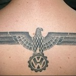 Фото татуировки на спине, изображающей орла с логотипом Volkswagen. Черно-серый рисунок татуировки с детальной проработкой.