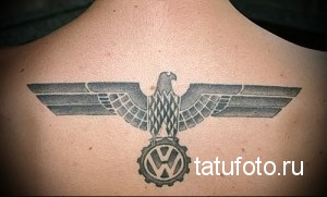 Фото татуировки на спине, изображающей орла с логотипом Volkswagen. Черно-серый рисунок татуировки с детальной проработкой.