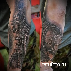 Фото тату спартанского воина на предплечьях в стиле реализм. Детальная проработка доспехов, шлема и щита. Черно-серые тона, эффект объема.