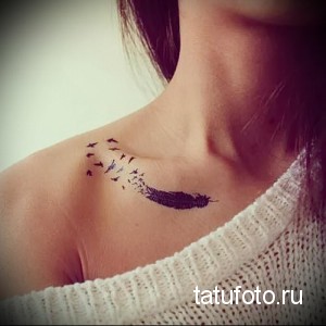 Фото тату: черное перо, из которого вылетают маленькие птицы, на плече девушки. Детализированный рисунок, плавные линии, черно-белый цвет.