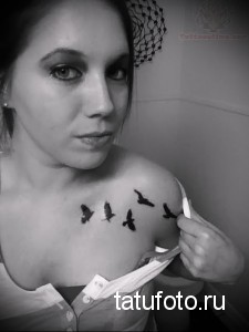 Фотография нескольких маленьких татуировок птиц, расположенных на плече девушки. Простой и элегантный рисунок татуировки.