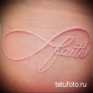 Фото тату: белая татуировка в виде знака бесконечности с надписью 'faith' на коже. Нежный и изящный рисунок.