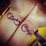 Фото тату: парные татуировки на запястьях в виде знаков бесконечности с надписями 'Love' и 'Strength'. Черный контурный рисунок.