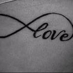 Фото тату: татуировка в виде знака бесконечности с надписью 'love' внутри. Черный контурный рисунок на коже.