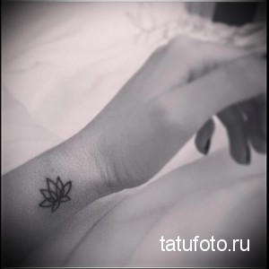 Фото тату: маленький цветок лотоса, выполненный в черном цвете на запястье. Простой и элегантный рисунок татуировки для любителей минимализма.