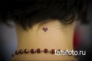 Фото тату маленького розового сердечка на затылке девушки. Нежный и минималистичный рисунок татуировки.