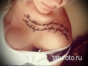 Фото тату надписи 'She is clothed in strength and dignity. And she laughs without fear of the future' на ключице. Женственная татуировка.