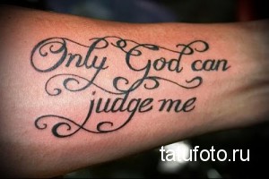 Фото тату на руке с надписью "Only God can judge me" выполненной красивым шрифтом с декоративными элементами.
