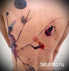 Фото тату на спине в стиле акварель. Размытые пятна синего, фиолетового и красного цветов, тонкие черные линии.