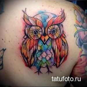 Фото тату акварельной совы на плече. Яркий и красочный рисунок, выполненный в технике акварели. Идея для оригинальной и символичной татуировки.