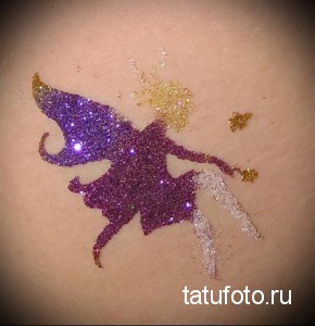 Фото тату на коже: изображение феи, выполненное блестками в фиолетовых, золотых и серебристых тонах. Сказочный и привлекательный дизайн.