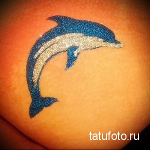 Фото тату: татуировка дельфина на коже. Блестящий эффект, яркие цвета, морская тематика.