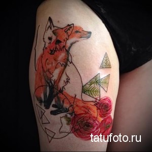 Фото тату: акварельное изображение лисы с розами на бедре, выполненное в теплых оранжевых и красных тонах с использованием техники размытия.