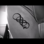 Фото татуировки на боку в виде символа бесконечности с надписью 'forever' под ним. Черно-белое изображение, простой и лаконичный стиль.