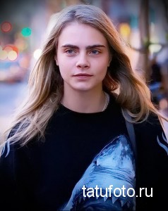 Фотография модели в черной футболке с изображением акулы, демонстрирующая современный и смелый образ.