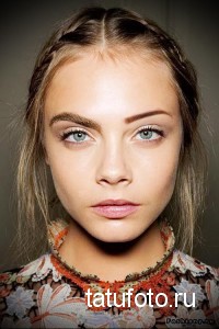 Фотография молодой модели с выразительными глазами и аккуратным плетением волос, демонстрирующая естественный макияж и свежий вид.
