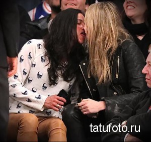 Фото тату: девушка с татуировкой черепов на рукаве целует Кару Делевинь на баскетбольном матче.