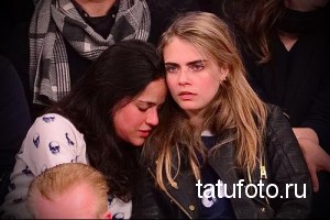 Фото тату: Кара Делевинь прислонилась к девушке с татуировкой черепов на рукаве, сидящей на баскетбольном матче.