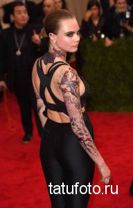 Фото тату: модель Cara Delevingne демонстрирует масштабную татуировку в стиле ирреалистичной сакуры, покрывающую шею, плечи и руки.