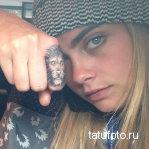 Крупный план татуировки с изображением головы льва на пальце модели, демонстрирующий детализированную проработку рисунка.