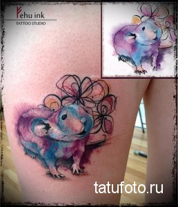 Фото акварельной татуировки хомяка на плече. Рисунок выполнен в нежных пастельных тонах, с изображением цветов.