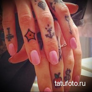 Фото тату на пальцах: маленькие изображения креста, звезды, якоря, розы, яблока и знака доллара в ярких цветах.