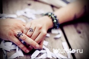Фото парных тату на пальцах: два четырехлистных клевера, расположенных на пальцах двух людей. Символичные рисунки татуировок в черном цвете.