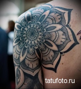 Фото татуировки мандалы, частично покрывающей плечо. Детализированный рисунок в технике дотворк с использованием градиентов серого.