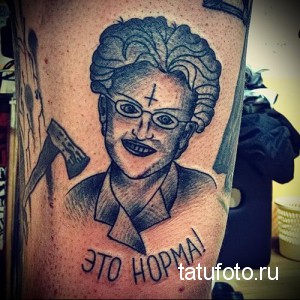 Фото татуировки на руке с изображением Бабы Яги с топором и надписью 'Это норма!'. Черно-серый рисунок в стиле реализм.