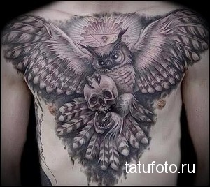 Фотография большой татуировки совы, держащей в когтях череп, выполненной на груди и спине. Детализированный рисунок татуировки в стиле реализм.