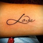 Фото тату бесконечности с надписью 'Love' на предплечье. Черно-белый рисунок, выполненный тонкими линиями, символизирует вечную любовь и преданность.