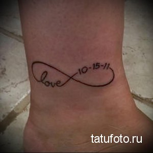 Фото тату бесконечность с надписью 'love 10-15-11' на лодыжке. Черно-коричневый рисунок, минималистичный стиль, татуировка с датой.