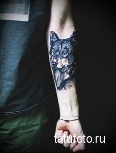 Фото тату на руке с изображением головы волка, выполненной в геометрическом стиле с использованием черных линий и треугольников.