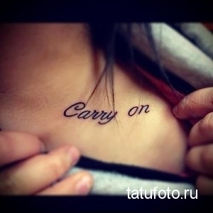 Фото тату надписи "Carry on" на ключице. Рисунок татуировки выполнен в черном цвете с использованием каллиграфического шрифта.