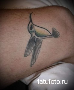 Фото тату: простая и минималистичная татуировка колибри на руке, выполненная в черно-серых тонах. Небольшой рисунок татуировки.