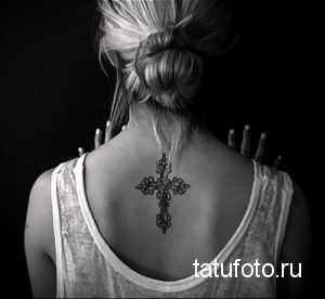 Фото татуировки креста на спине девушки, выполненной в черном цвете. Изящный рисунок татуировки, подходящий для тех, кто ищет минималистичный эскиз.