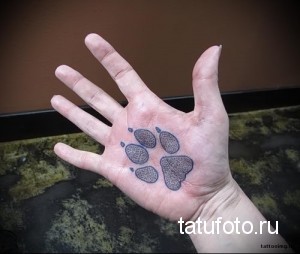 Фото тату отпечатка лапы на ладони. Маленький, минималистичный рисунок в черном цвете. Простой и элегантный дизайн.