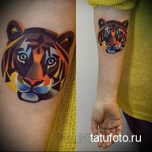 Фото тату головы тигра в геометрическом стиле на руке. Яркие оранжевые, черные и голубые цвета. Уникальный рисунок татуировки.