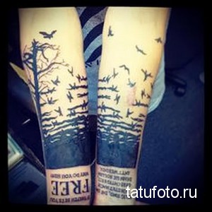 Фото тату: татуировка на обеих руках с изображением леса, летящих птиц и надписи 'FREE', выполненная в черно-серых тонах с акцентом на детализацию.
