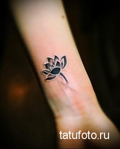Фото тату: Черно-белый рисунок лотоса на предплечье, выполненный в технике blackwork, с акцентом на детализацию и контраст.