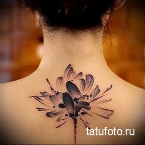 Фото татуировки на задней части шеи с изображением цветка лотоса, выполненного в технике акварели. Нежные переходы цветов и размытые контуры.